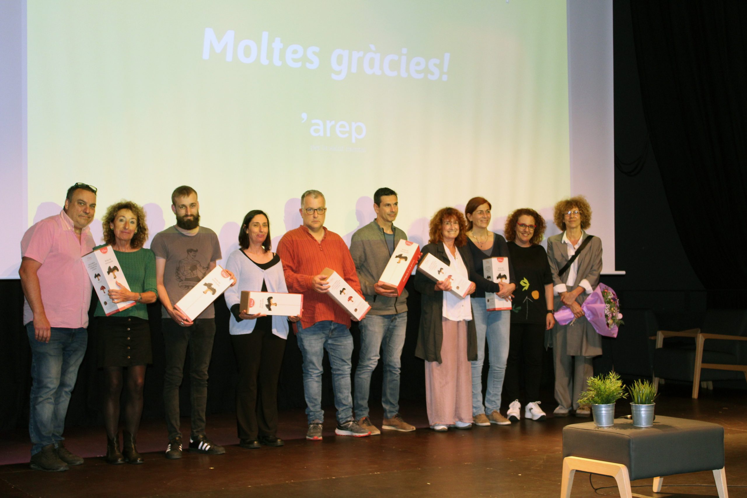 Foto de grup de les persones que van participar a les xerrades, sostenint el seu obsequi d'agraïment.