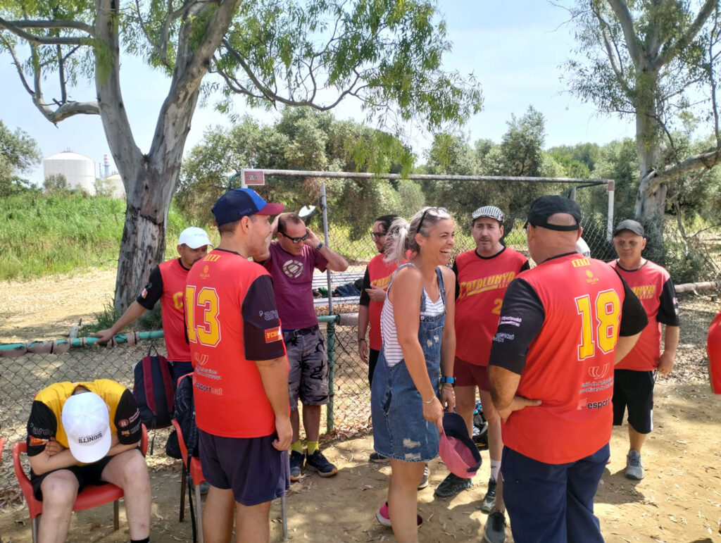 Un grup de persones, algunes equipades per jugar a softbol, xerrant.