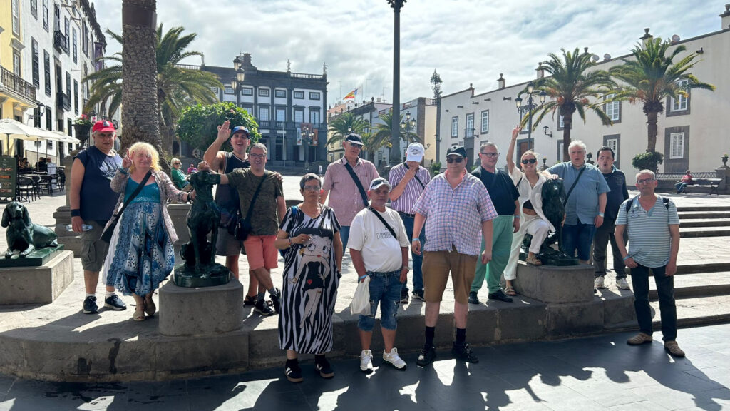 Foto de grup del Club Social, en un carrer assolellat amb palmeres al darrere.