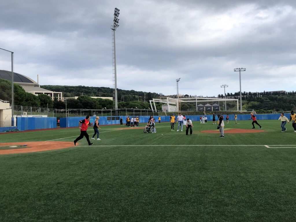 Persones jugant a softbol en un camp, algunes corrent i altres en posició, gaudint del joc a l'aire lliure.