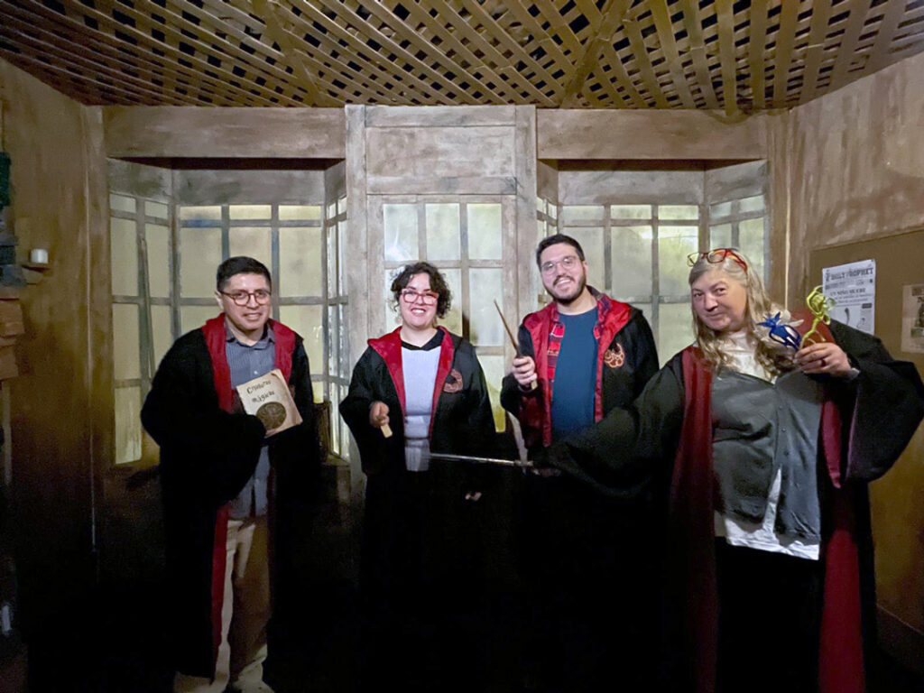 Foto de grup de quatre persones amb disfresses de la saga Harry Potter, en una habitació fosca amb parets de fusta.