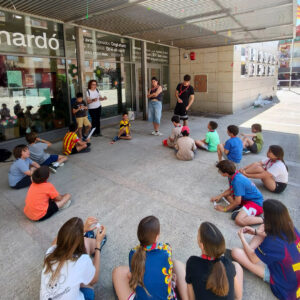 Un grup d'adolescents asseguts en rotllana escoltant l'explicació d'una persona adulta.