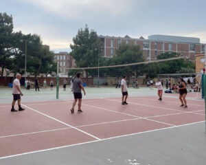 Un camp de voleibol amb persones jugant i edificis urbans al fons