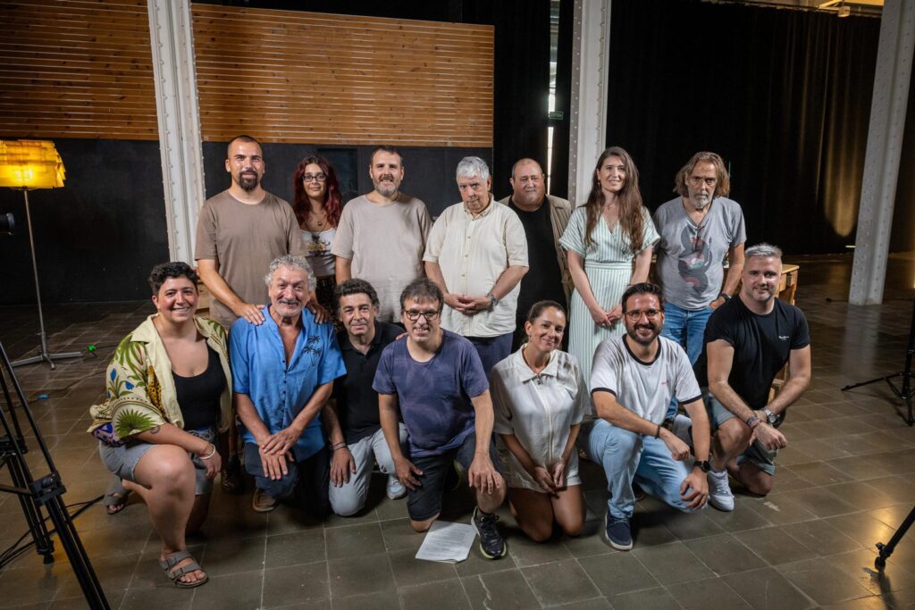 Foto de grup d'una dotzena de persones de diferents edats i gèneres, en un estudi de gravació.