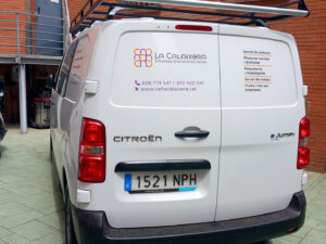 La part del darrere d'una furgoneta amb retolació. A la part esquerra, el logotip de La Calaixera i la informació de contacte. A la dreta, els serveis.