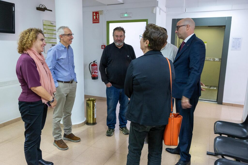 Grup de persones conversant en una sala, mostrant interacció i comunicació entre els participants.