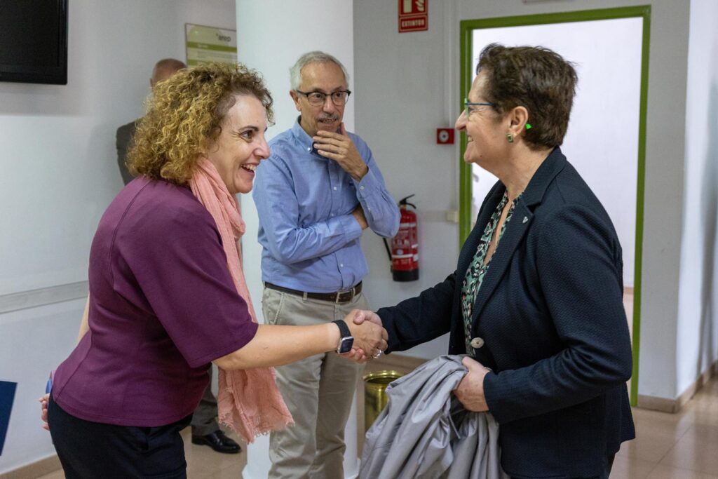 Dues dones encaixant-se la mà en un passadís, mostrant un gest d'acord o salutació professional.