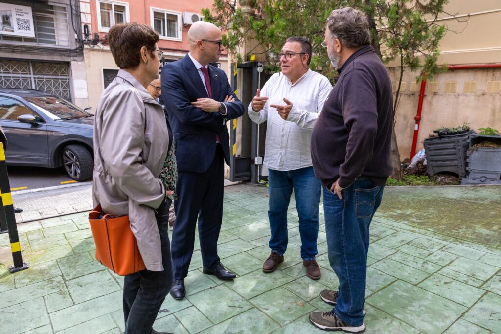 Un grup de cinc persones es saluda formalment en un pati de rajoles verdes